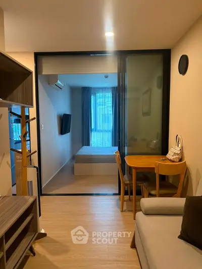 Modern apartment interior with cozy living room and bedroom view, featuring stylish furniture and wooden flooring.