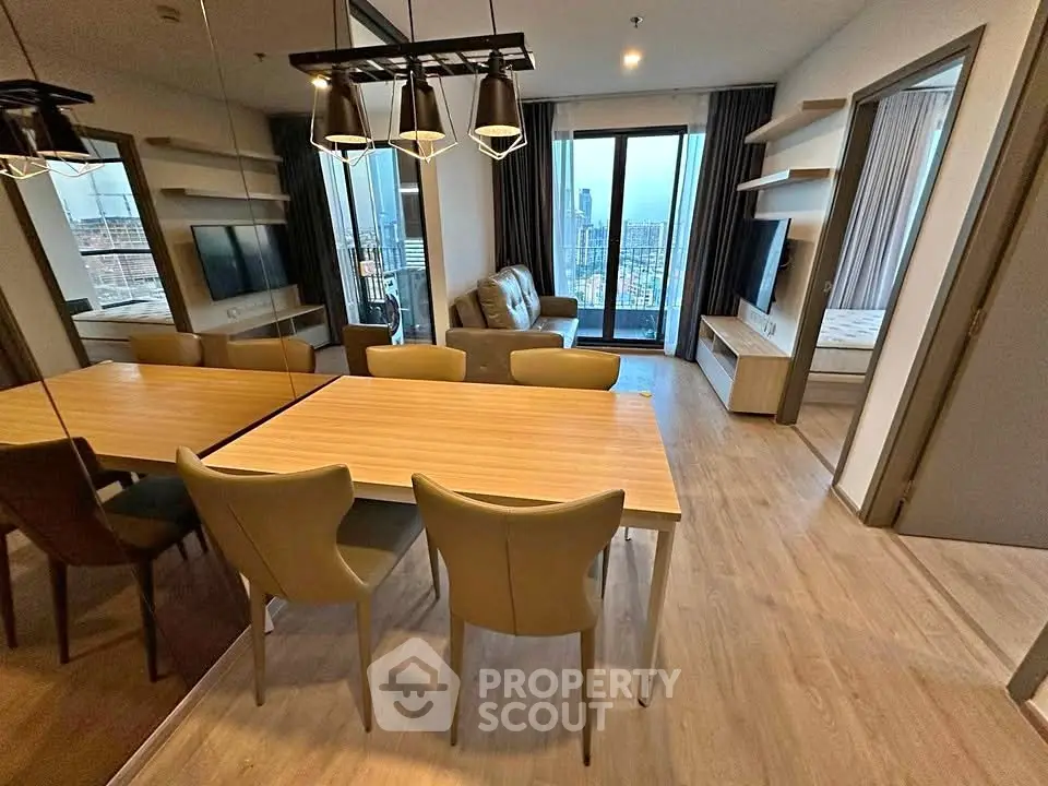 Modern open-plan living and dining area with city view, featuring stylish furniture and large windows.