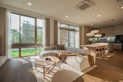 Spacious modern living room with open kitchen and large windows overlooking garden.