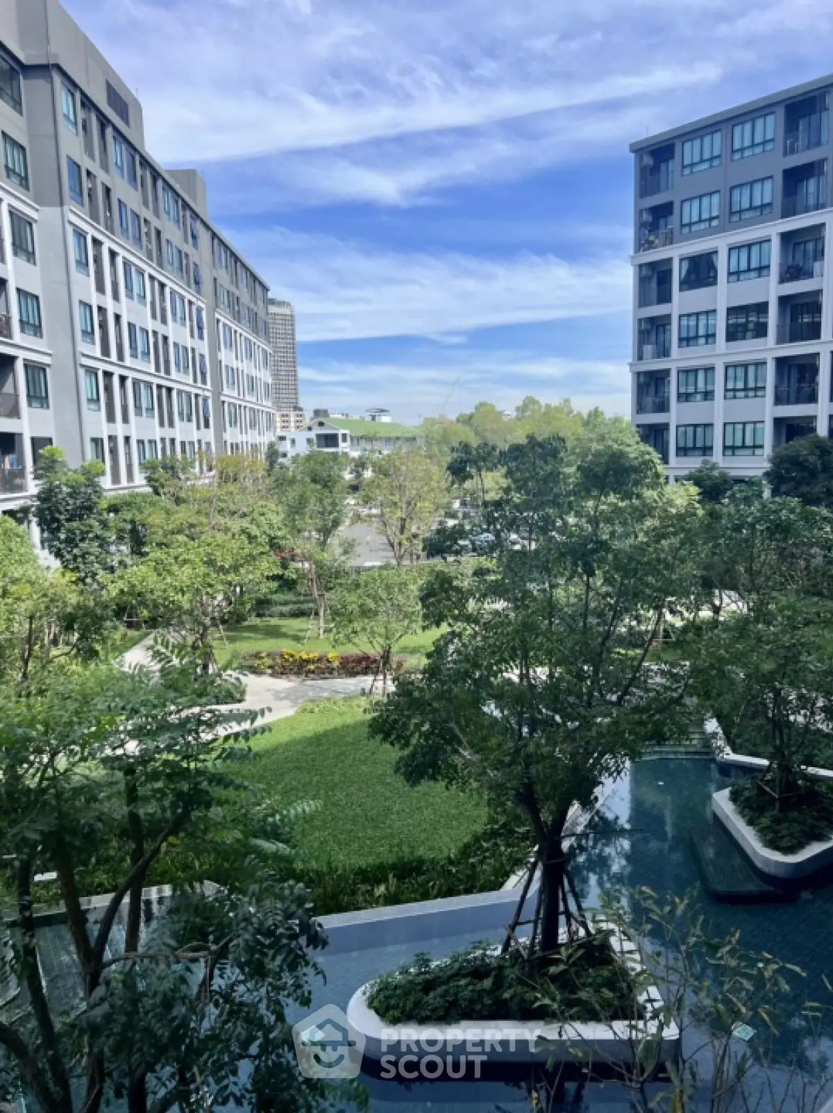 Luxurious modern apartment complex with lush green garden and serene water features.