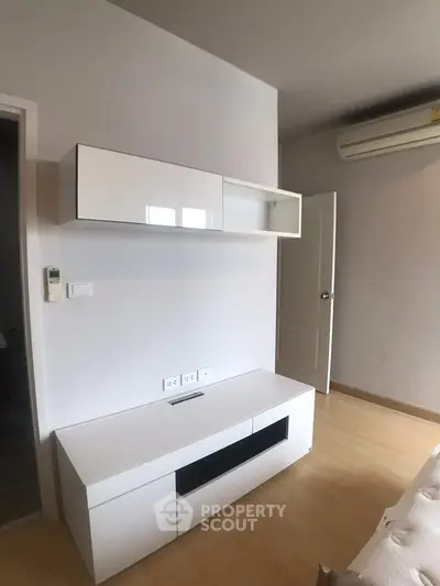 Modern living room with sleek white furniture and air conditioning unit