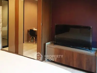 Modern bedroom with sleek wooden furniture and large TV, perfect for relaxation.