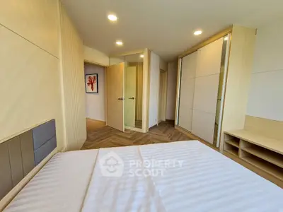 Modern bedroom with stylish decor and ample natural light, featuring built-in wardrobes and elegant wood flooring.