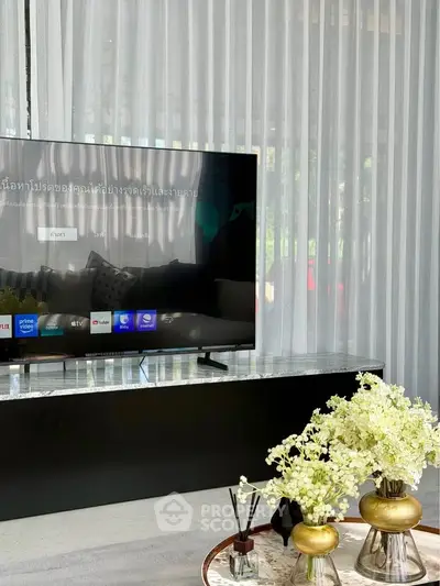 Modern living room with large TV and elegant decor in a stylish home.