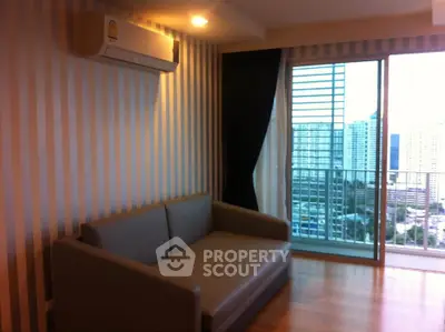 Modern living room with striped wallpaper, cozy sofa, and city view from balcony.