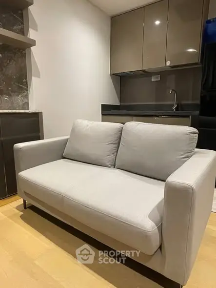 Modern compact living room with sleek sofa and kitchenette