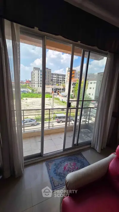 Spacious balcony with sliding glass doors offering a vibrant city view, perfect for urban living.