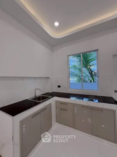 Modern kitchen with sleek cabinets and large window offering natural light