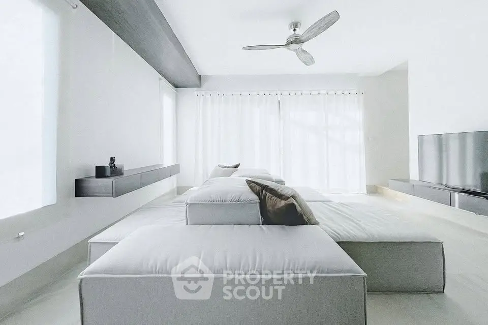 Modern minimalist living room with sleek furniture and ceiling fan