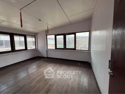 Spacious empty room with large windows and wooden flooring, ideal for customization.