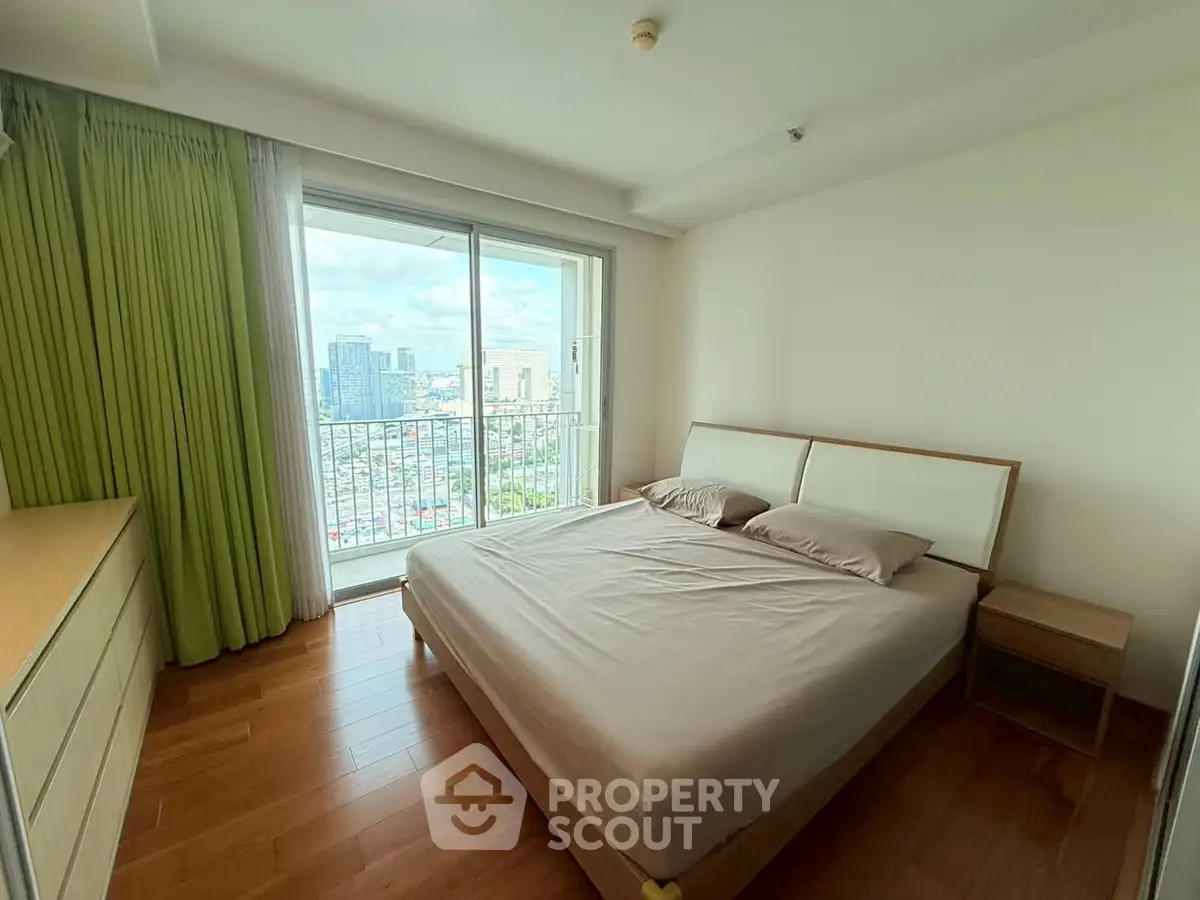 Spacious bedroom with city view and balcony access in modern apartment
