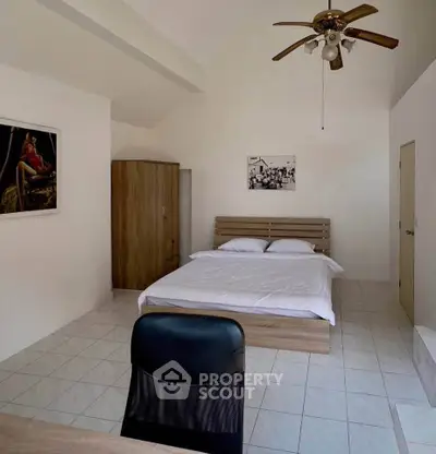 Spacious bedroom with modern decor and ceiling fan, ideal for comfort and relaxation.