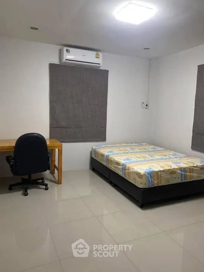 Minimalist bedroom with bed, desk, and air conditioning unit.