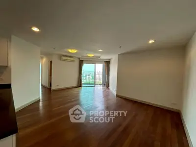 Spacious living room with wooden floors and balcony view in modern apartment