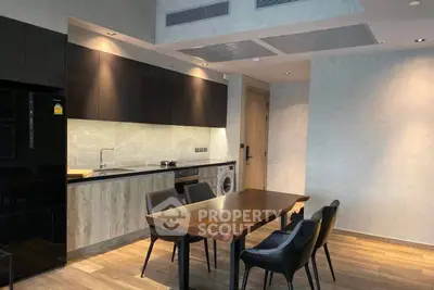 Modern kitchen with sleek design and dining area in open layout apartment.