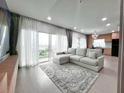 Spacious modern living room with large windows and open kitchen layout, offering a stunning city view.