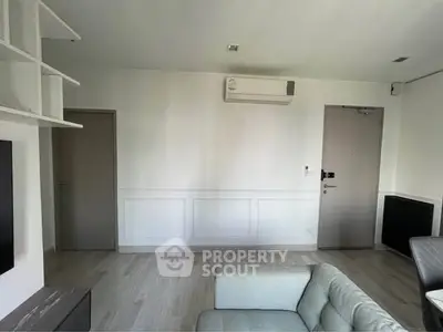 Modern living room with sleek design and air conditioning unit, featuring neutral tones and minimalist decor.