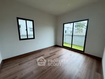 Spacious empty room with large windows and wooden flooring in modern home.