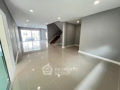 Spacious modern living room with glossy tiled floors and staircase