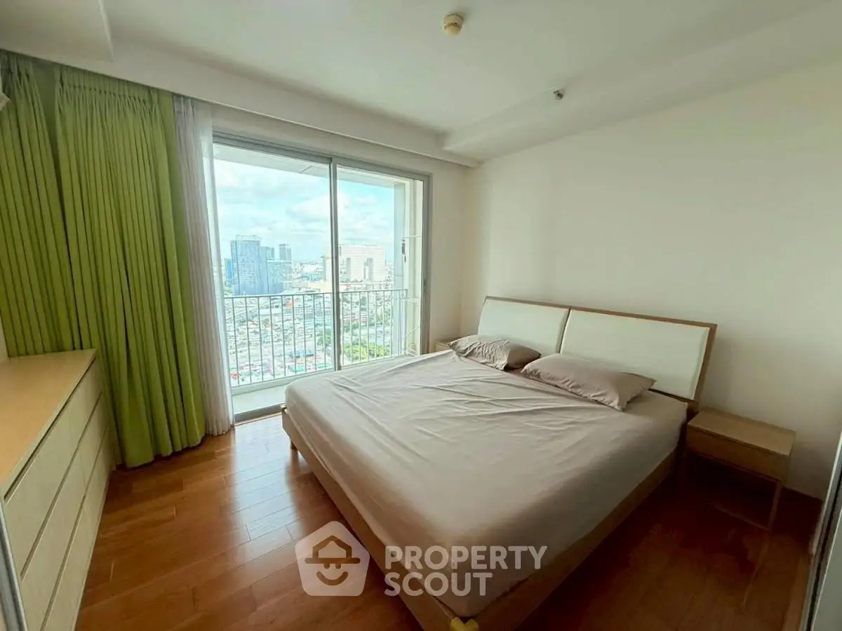 Spacious bedroom with city view and large window, perfect for relaxation.
