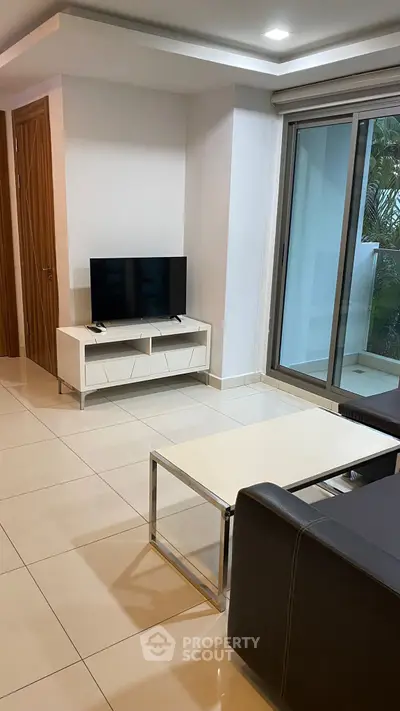 Modern living room with sleek furniture and large sliding glass doors to balcony.
