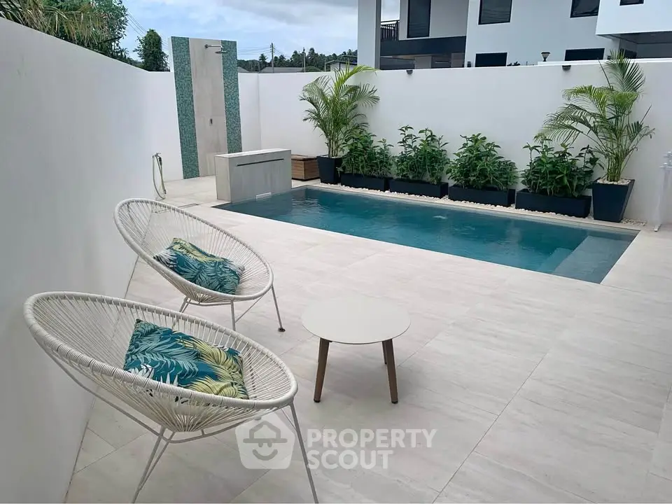 Modern outdoor pool area with stylish seating and lush greenery, perfect for relaxation and entertainment.