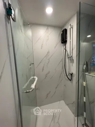 Modern bathroom with marble walls and glass shower enclosure
