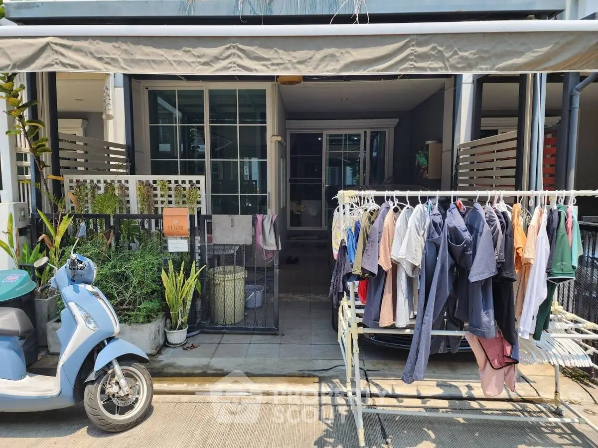 Charming townhouse entrance with clothes drying area and scooter parking.