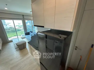 Modern apartment interior with sleek kitchen and spacious living area featuring large windows and city view.