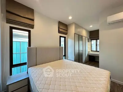 Modern bedroom with large windows, stylish headboard, and ample storage space in a contemporary home.