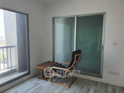 Modern minimalist room with chair and table, large windows, and balcony view.