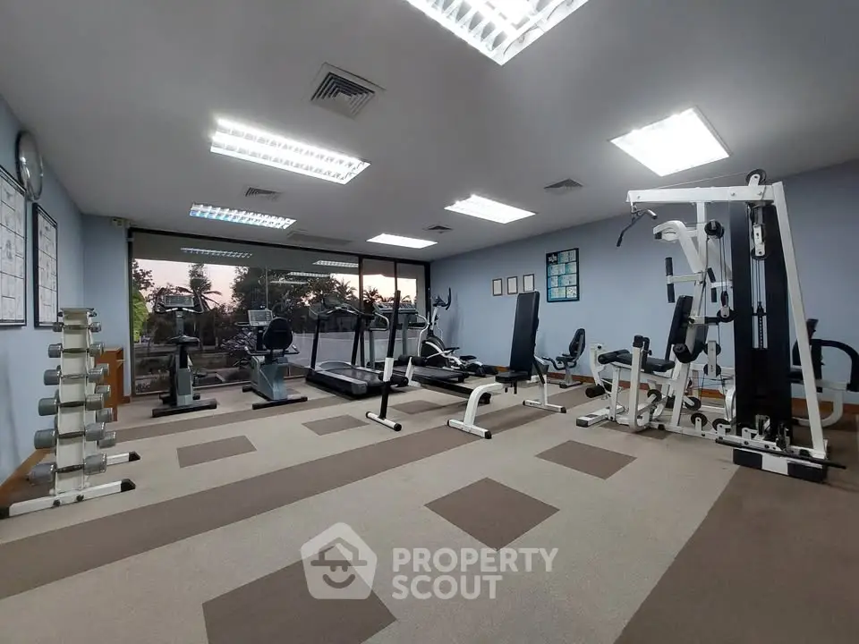 Spacious gym with modern equipment and large windows offering a scenic view.