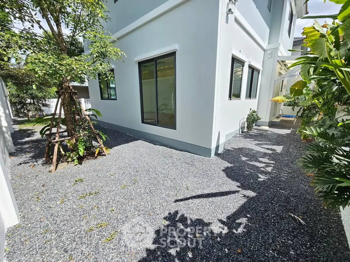 Modern residential building exterior with gravel pathway and lush greenery