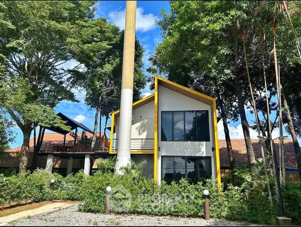 Modern two-story house with unique yellow trim and lush greenery
