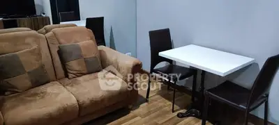 Cozy living room with brown sofa and dining table, perfect for small gatherings.