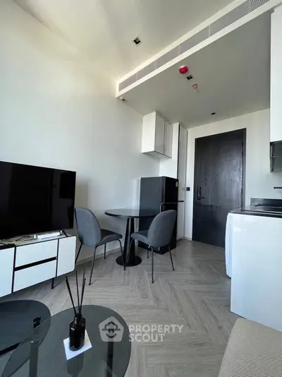 Modern living room with sleek furniture and minimalist design, featuring a TV and dining area.