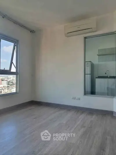 Modern apartment with wooden flooring and city view, featuring a compact kitchen area.