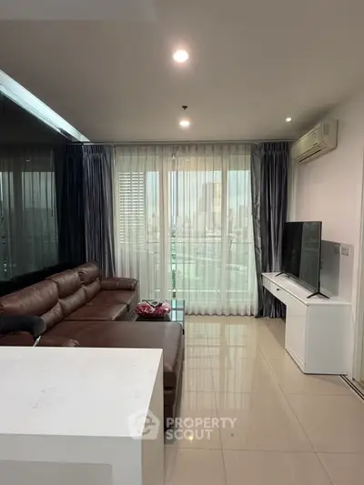 Modern living room with city view, featuring a leather sofa and large TV, perfect for urban living.