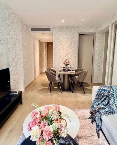 Stylish living room with modern decor and elegant dining area, featuring chic furniture and floral accents.