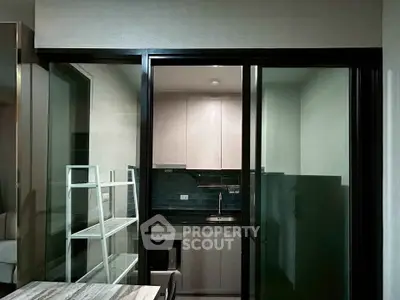 Modern compact kitchen with sleek cabinetry and sliding glass doors in a contemporary apartment.