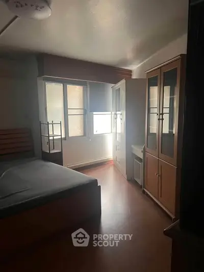 Cozy bedroom with natural light and wooden furniture, perfect for relaxation.