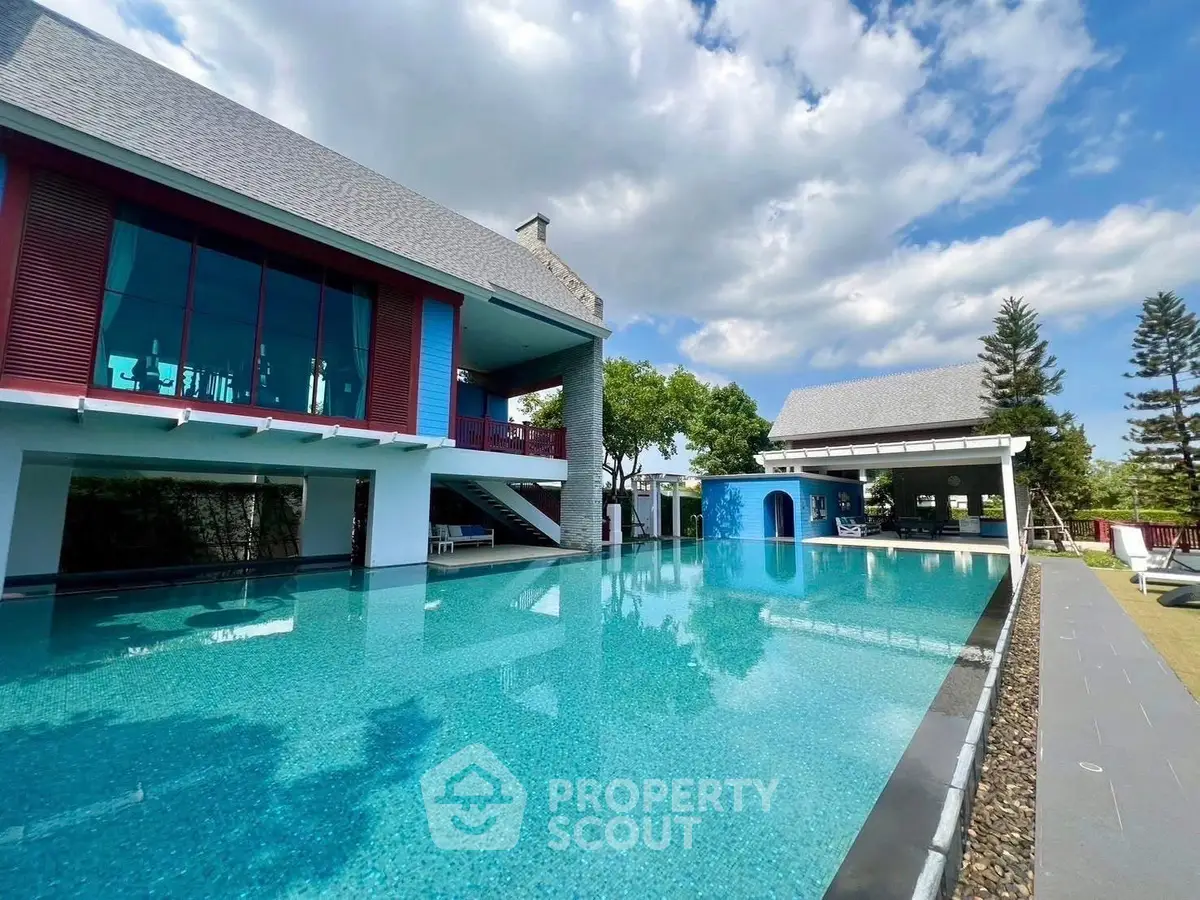 Luxurious modern home with stunning pool and spacious outdoor area under clear blue skies.