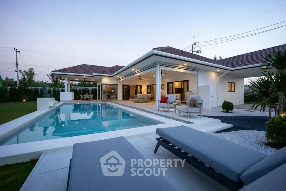 Luxurious modern villa with pool and spacious outdoor seating area at sunset.