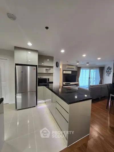 Modern open-layout kitchen with sleek appliances and spacious living area in a stylish apartment.