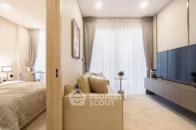Modern living room with sleek TV setup and cozy beige sofa, adjacent to a stylish bedroom.