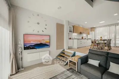 Modern open-plan living room with stylish kitchen and dining area, featuring sleek furnishings and natural light.