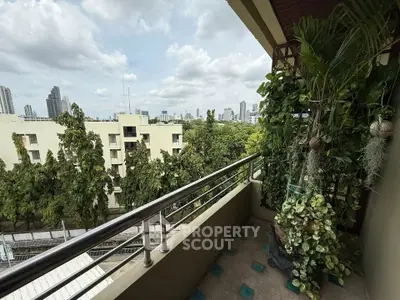 Spacious balcony with lush greenery and city skyline view, perfect for relaxation and enjoying urban living.