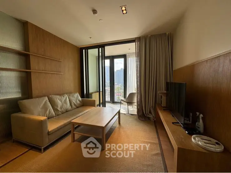Modern living room with balcony view, featuring sleek furniture and natural light.