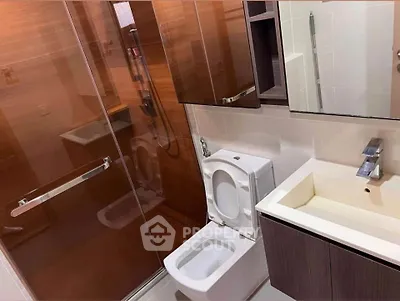 Modern bathroom with glass shower and sleek fixtures in contemporary apartment.