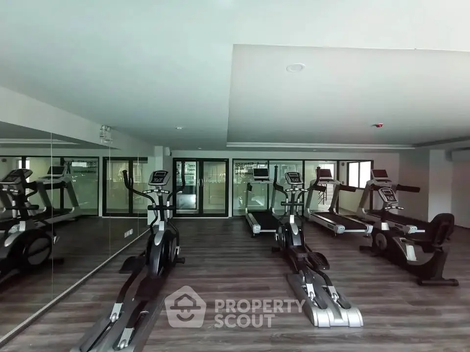 Modern gym with state-of-the-art exercise equipment and mirrored walls in a luxury apartment complex.